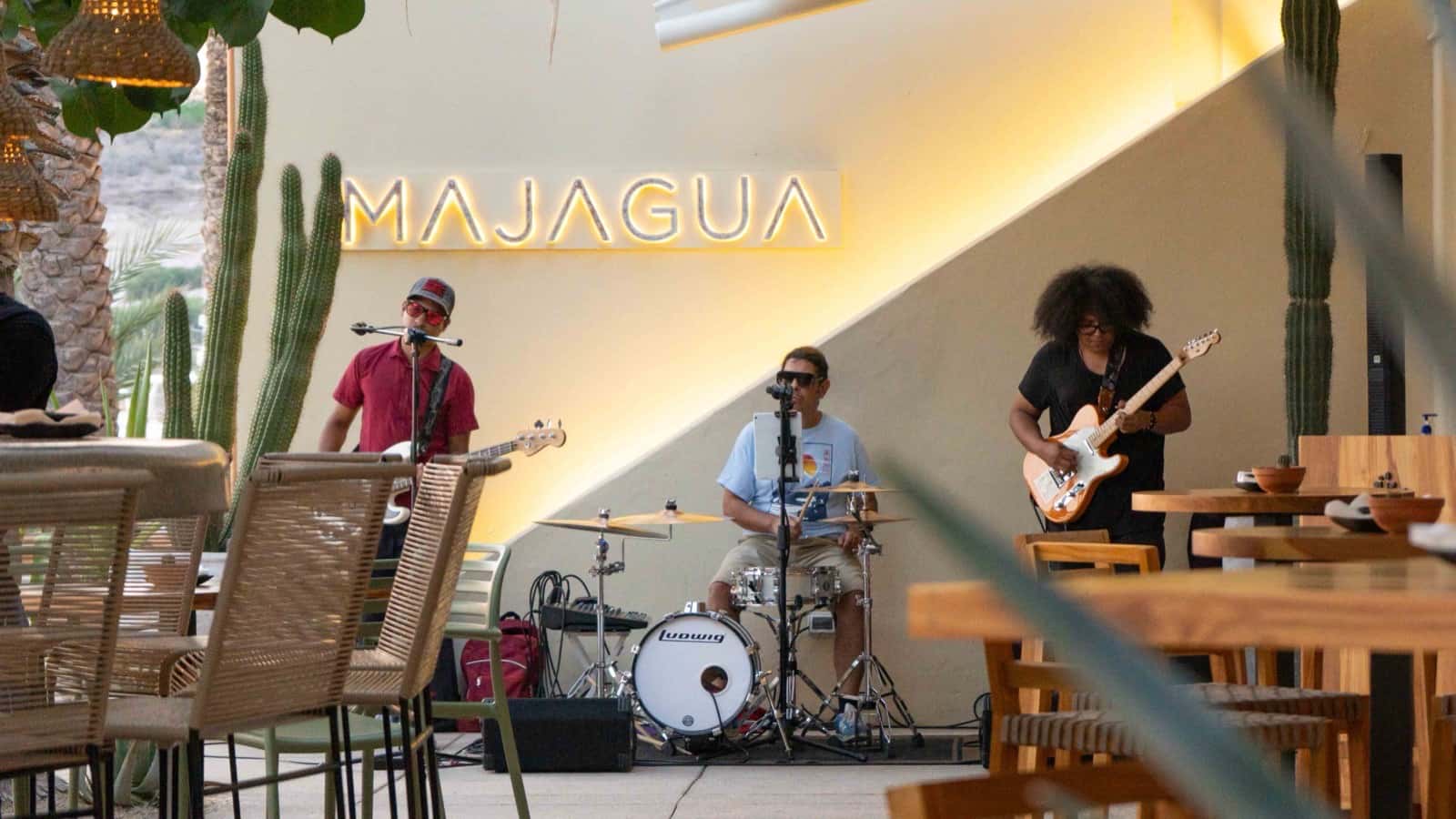 Un trío toca en vivo bajo el letrero de Majagua, entre las mesas